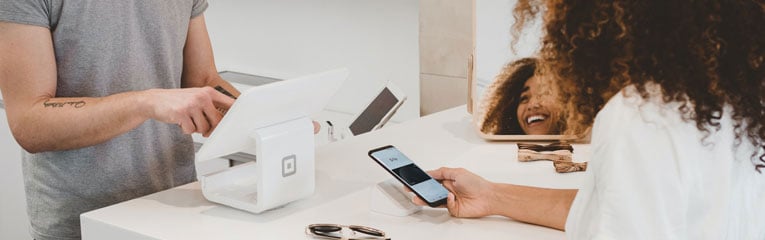 Woman-using-her-digital-wallet-on-her-cell-phone-to-buysunglasses-at-a-boutique