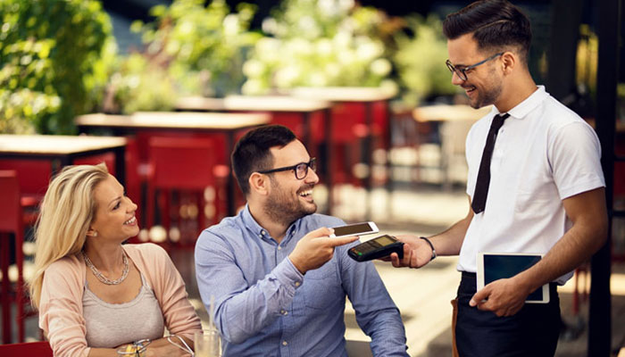  Couple-paying-a-waiter-for-dinner-at-a-resstuarant-using-their-digital-wallet-on-their-cellphone. 