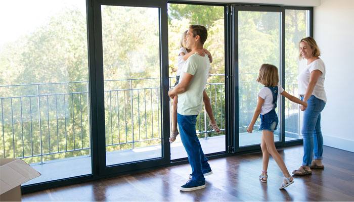 Family-wondering-what-to-look-for-when-buying-a-house-as-they-look-out-a-large-window-of-a-potential-new-home.