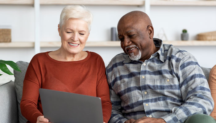 Older-couple-sitting-on-a-couple-researching-should-i-refinance-my-mortgage-on-a-laptop.